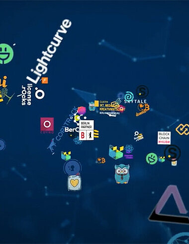 Logowall von Berliner Blockchain-Unternehmen vor blauem Hintergrund.